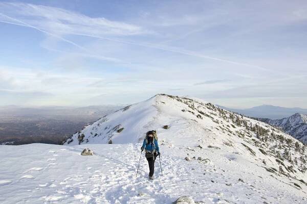 A hiker poses in front of the snow-capped summit of Mount San Antonio.