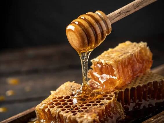 A close-up of a Honeycomb piece with beeswax and honey dripping, showcasing its natural structure, placed on a rustic wooden board.