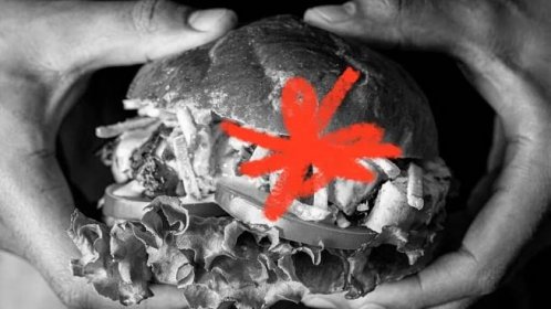 Black and white image of a person's hands holding a burger with a red scribble mark over the burger