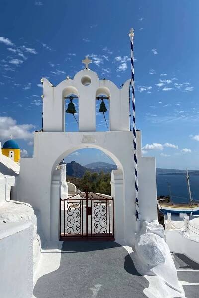church door in oia wit two bells and a door with sa in the background
