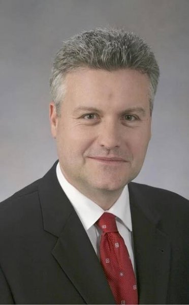doctor vieweg in a dark suit with a white shirt and red patterened tie.  