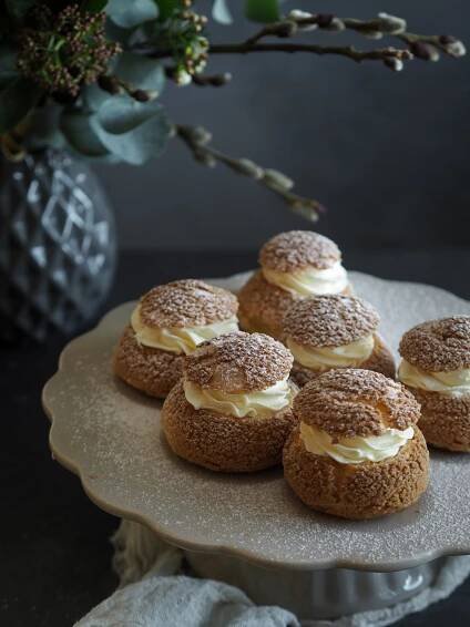 several small pastries on a plate with flowers in the backgroung behind them