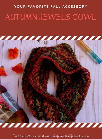 An autumn crochet cowl laid in a circle with a crochet hook, orange flowers, and yarn in the background.