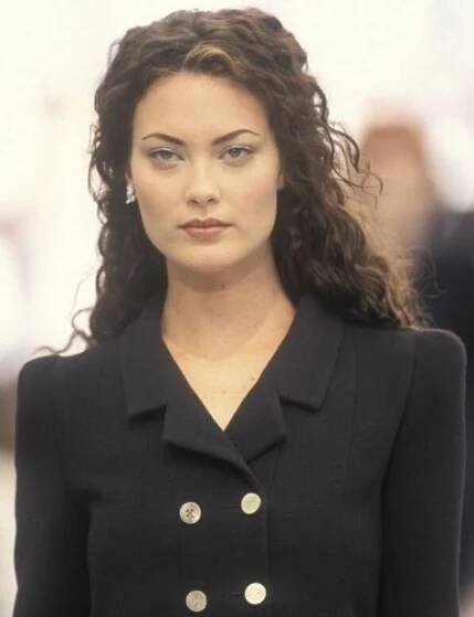 a woman with long hair wearing a black jacket and gold buttons on her lapel