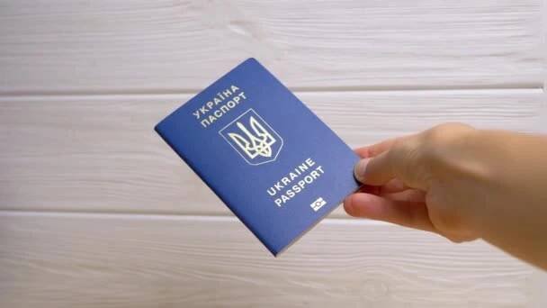 Žena Ruka drží modrý biometrický pas Ukrajiny na bílém pozadí. Inscription in Ukrainian Ukraine Passport. Dívka ukazuje obdržené mezinárodní doklad pro cestování do zahraničí, cestování. — Stock záběr