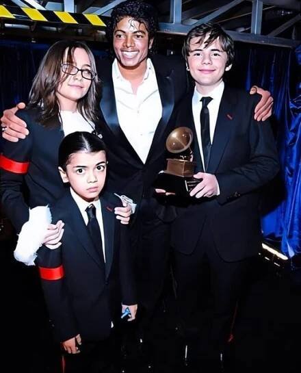 a group of people standing next to each other in front of a blue curtain holding an award