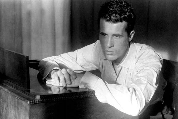 Portrait of American film director Kenneth Anger seated at a piano, Los Angeles, California, 1955. 