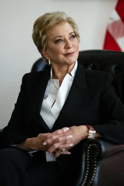 A portrait of Linda McMahon seated while wearing a black blazer and white shirt.