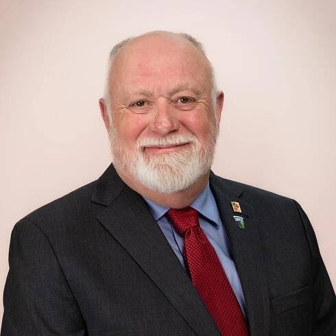 Councillor Carl MacPhee, a smiling man with light skin, white hair, white beard, and brown eyes