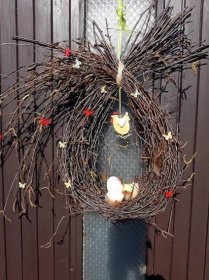 a grapevine wreath with eggs hanging from it's side on a metal pole