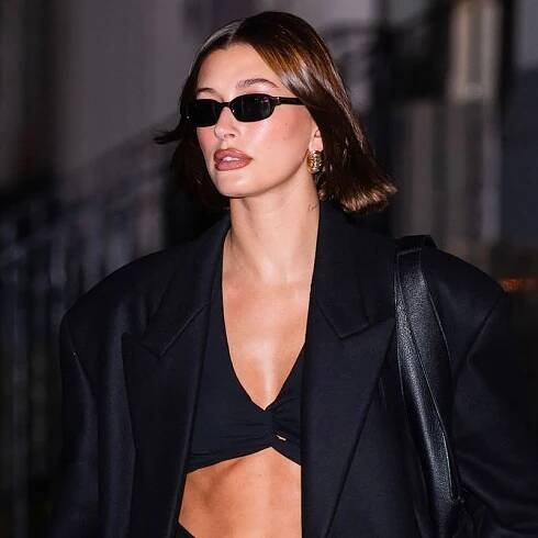 Hailey Bieber wears oval sunglasses and a black blazer