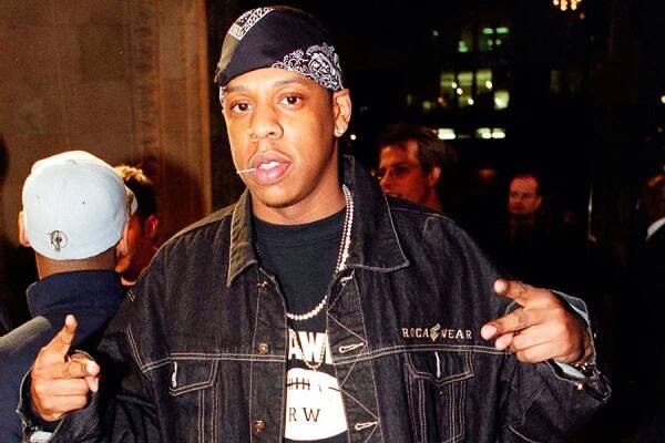 jay-z puts up peace signs, blue bandana rocawear jacket and a chain toothpick in mouth