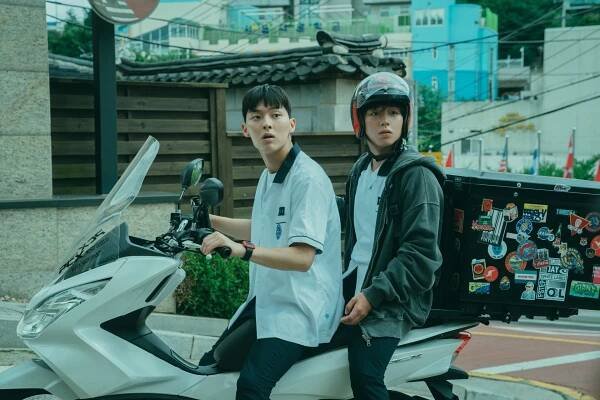A teen in a school uniform (Choi Hyun-wook as Ahn Su-ho) drives a delivery scooter as another teen wearing a helmet (Park Ji-hoon as Yeon Si-eun) rides with him, in 'Weak Hero Class 1.'