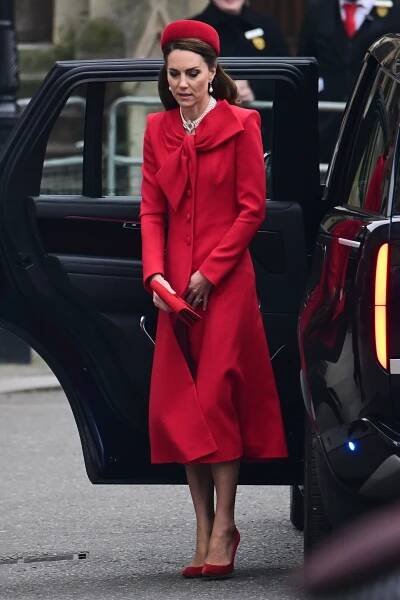 the queen is stepping out of her car wearing a red coat and matching hat as she arrives