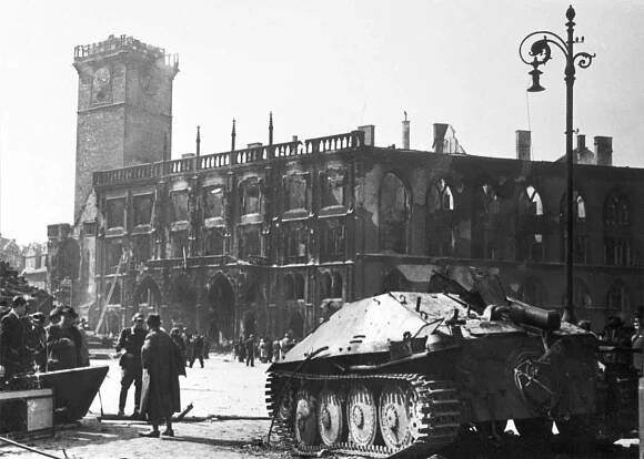 Povstalci zničili mnoho obrněných vozidel, včetně tohoto stíhače tanků Hetzer. V pozadí jde vidět vyhořelá staroměstská radnice.