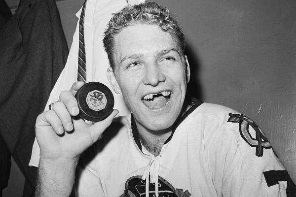 A grinning Bobby Hull, forward for the Chicago Blackhawks, holds up a puck in the locker room following a game against the New York Rangers at Madison Square Garden.