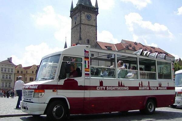 červenobiely autobus pred hodinovou vežou