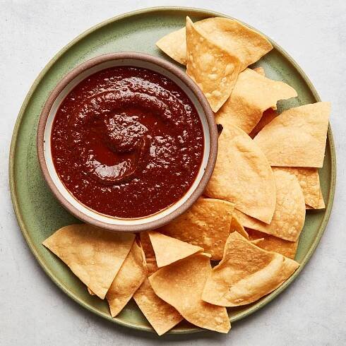 A bowl of salsa roja being served with tortilla chips.