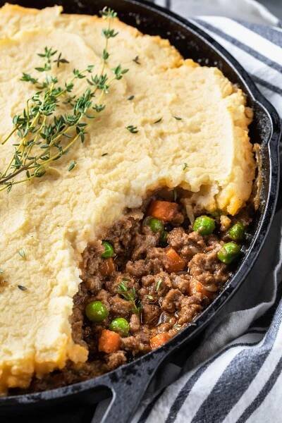 shepherd's pie with mashed potatoes and peas in a cast iron skillet