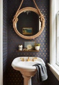bathroom with pedestal sink round mirror patterned wallpaper