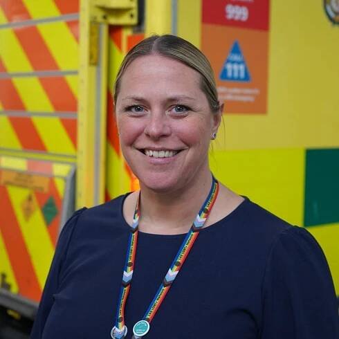 Clare McMillan standing in front of an ambulance.