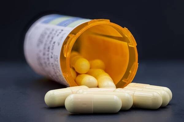 detailní snímek léků vytékajících z oranžové lahvičky na předpis na černém pozadí - antibiotikum - stock snímky, obrázky a fotky