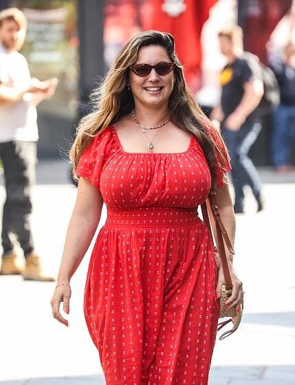 a woman in a red dress and sunglasses smiles for the camera