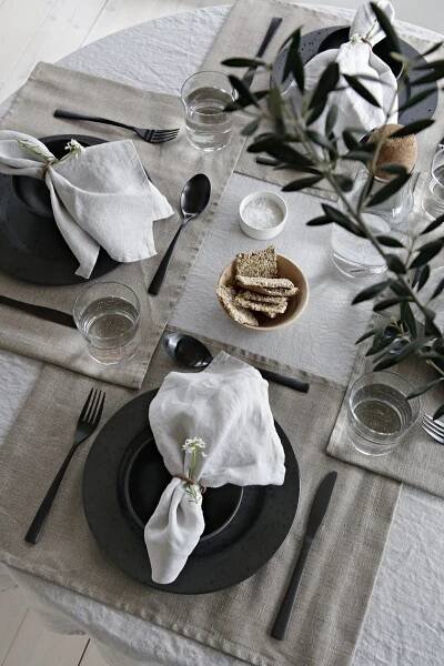 the table is set with black and white plates, napkins, silverware and flowers