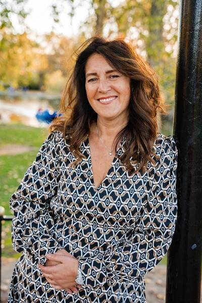 Woman leaning near a post in Regent's Park at golden hour.  Wearing a patterned dress.  More of a headshot. Autumn shoot 
