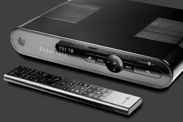 Studio photogaphy: Product photo of a media receiver of the Deutsche Telekom AG. The picture is almost exclusively black and white, but 4 buttons on the remote control are marked with colors.