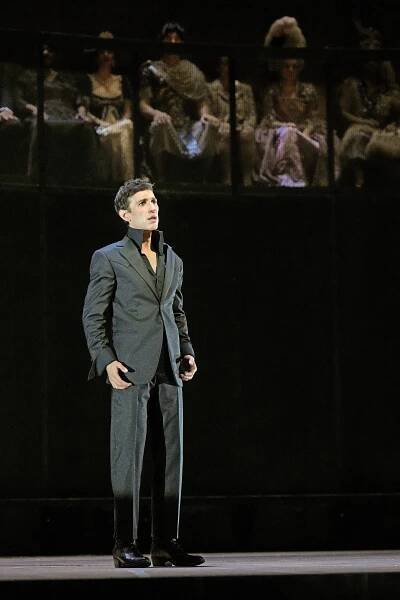 A man in a suit sings on stage