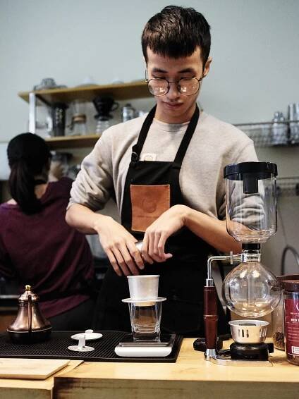 Young hip local barista at a Hanoi coffee shop making typical vietnamese coffee.