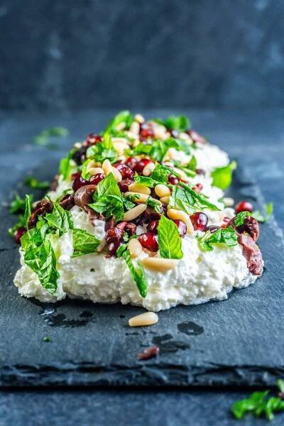 Creamy whipped feta dip on a serving plate with mint leaves strewn across the top; photographed from a side-angle