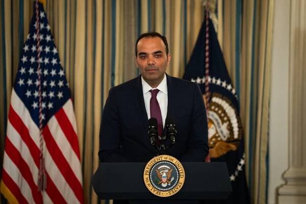 Rohit Chopra, standing at a lectern that holds two microphones and displays the presidential seal. 