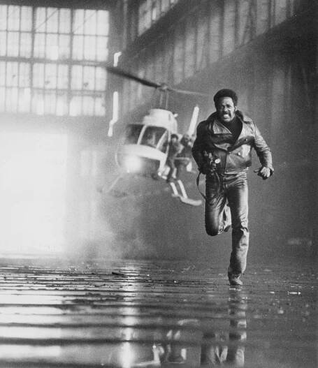 A black-and-white photo of Mr. Roundtree, as Shaft, running from a helicopter that is pursuing him.