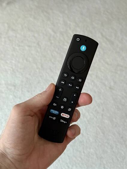 Hand holding a black Fire TV remote.