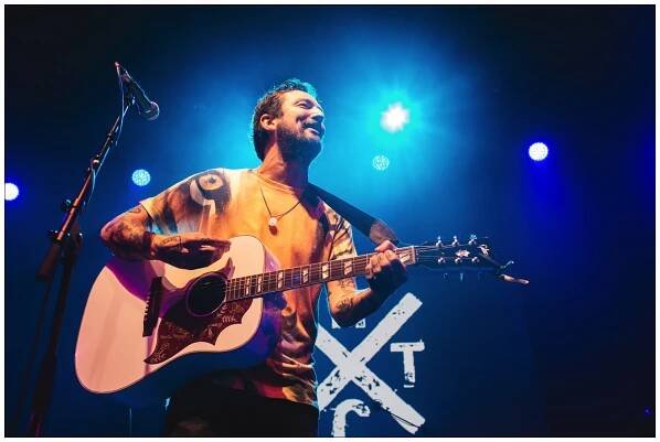 Frank Turner under blue lights on stage at A Peaceful Noise concert