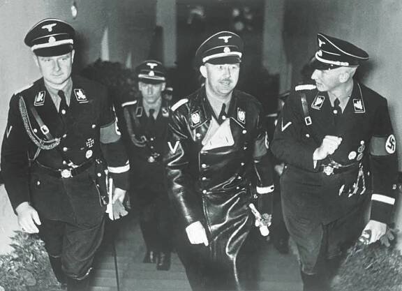 Wolff had a comfortable place in upper echelons of the Nazi Party and the SS: attending a 1936 film premiere with SS bigwigs Heinrich Himmler (center) and Reinhard Heydrich (right), and studying a map with Hitler (below), circa 1940. (AKG-Images)