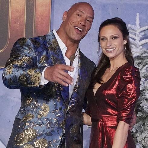 Dwayne Johnson and Lauren Hashian, 12 years apart in age, radiated style on the red carpet—he in a bold blue floral brocade tuxedo, she in a deep red metallic wrap dress with puffed sleeves and a plunging neckline