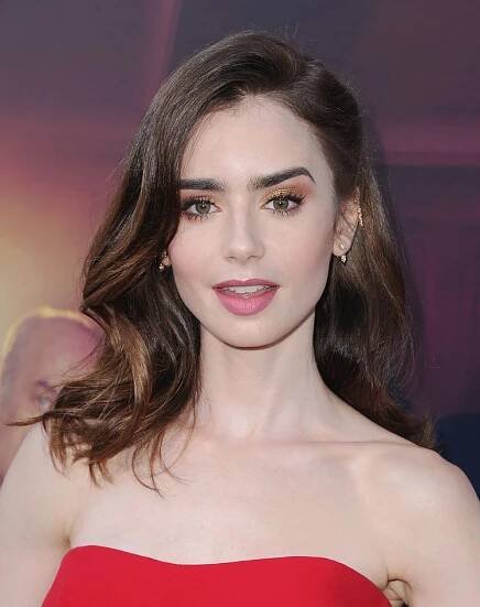 Lily Collins with shiny, wavy, shoulder-length hair with a side part