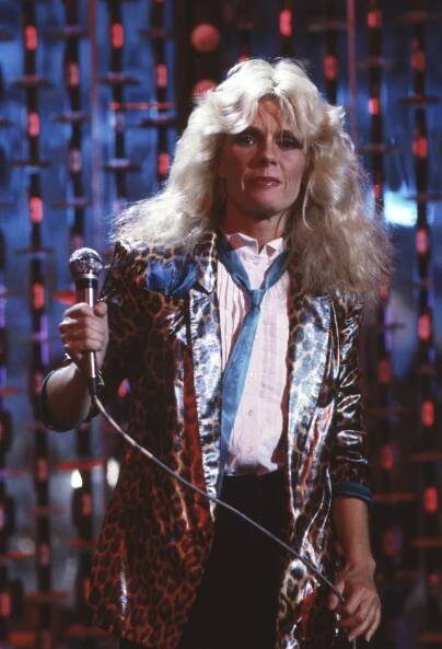 Kim Carnes with a microphone on stage.