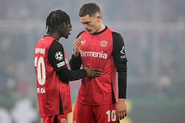 Bayer Leverkusen midfielders Jeremie Frimpong and Florian Wirtz talking during a soccer match.