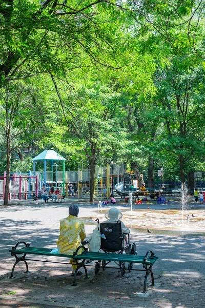 Elderly couple, one of whom is in a wheelchair, sit and watch kids play at Seward Park, best things to do lower east side