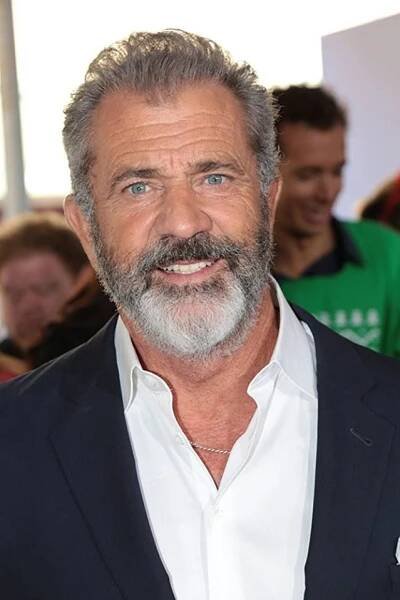a man with a beard and white shirt is smiling at the camera while people look on