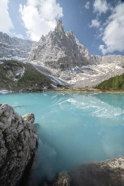 Punta Sorapis reflecting in the waters of the lake on a blue sky sunny day
