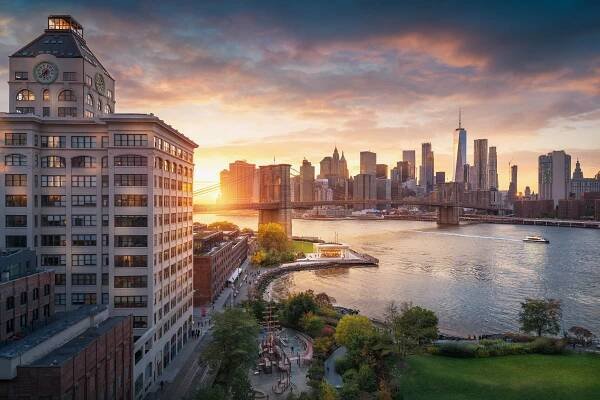 Slavný Brooklynský most v New Yorku s finanční čtvrtí - v centru Manhattanu v pozadí. Vyhlídková loď na východní řece a krásný západ slunce nad Janeovým karuselem.