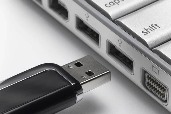 USB flash drive about to connect to laptop, close-up.