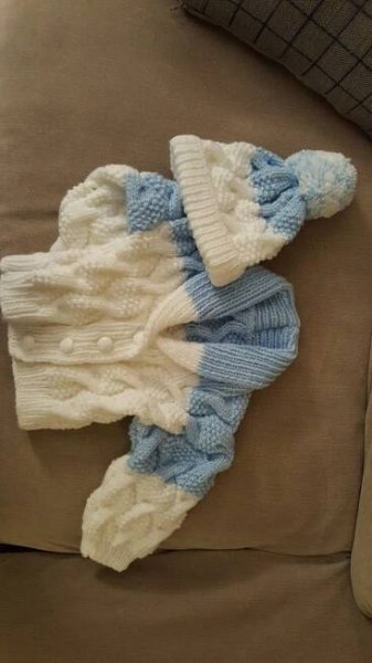 two knitted sweaters laying on top of a couch