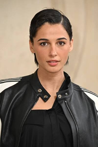 Person with short hair in a sleek black and white jacket, looking at the camera