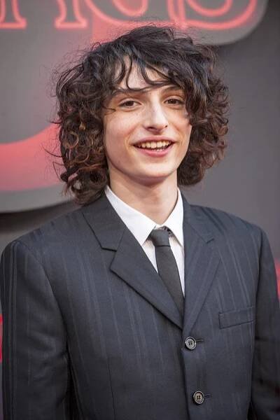 Download Finn Wolfhard Smiling On Stage Wallpaper